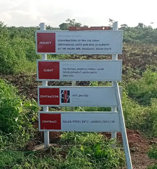 Project sign at the site listing the project as construction of ten 200 square metre greenhouse units and one nursery at the NALDA site, Shagamu, Ogun State; the client as the National Agricultural Land Development Authority (NALDA); the contractor as 617 Limited; and the contract reference as NALDA/PROC/INTV./WORKS/2024/38.